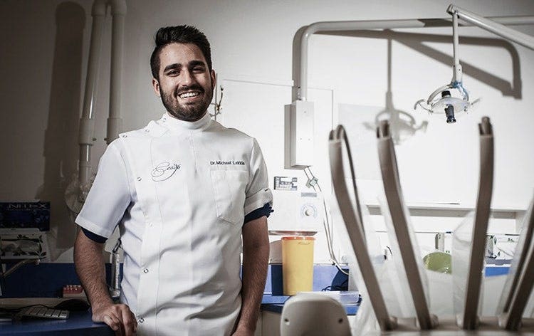 Dentist in white uniform standing in treatment room with dental instruments