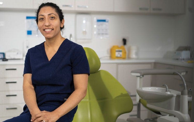 Clinician seated beside dental chair in clean treatment room